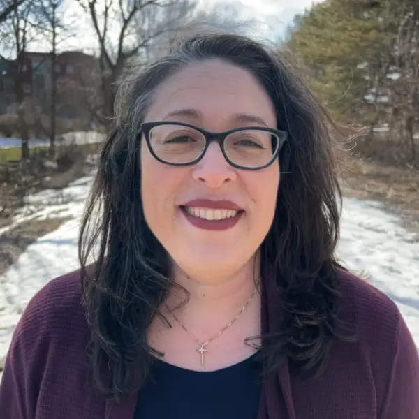 Regina Howland is smiling at the camera with snow and trees in the background.