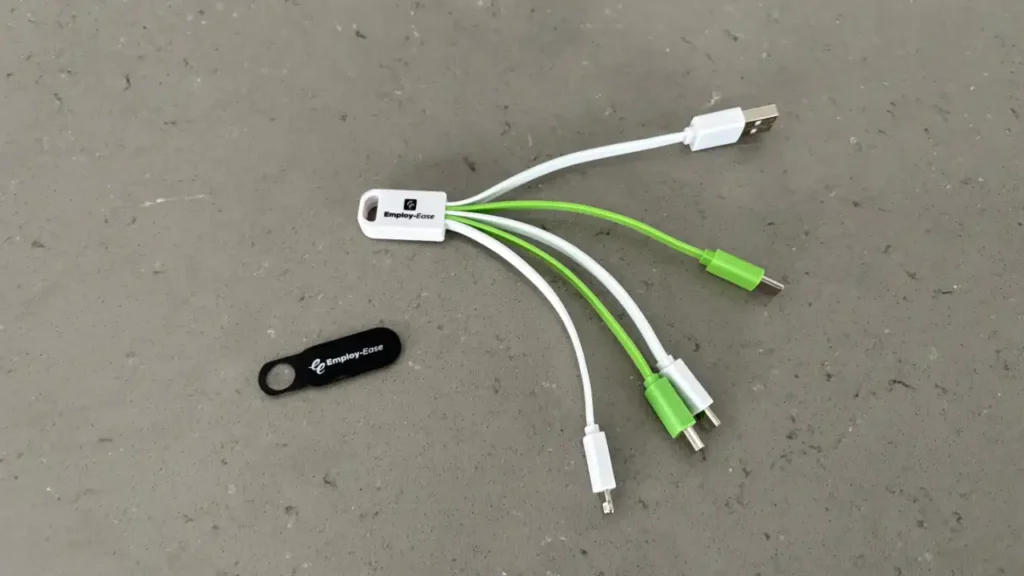 A webcam cover and 3-in-1 charging cable with the Employ-Ease logo printed on them.