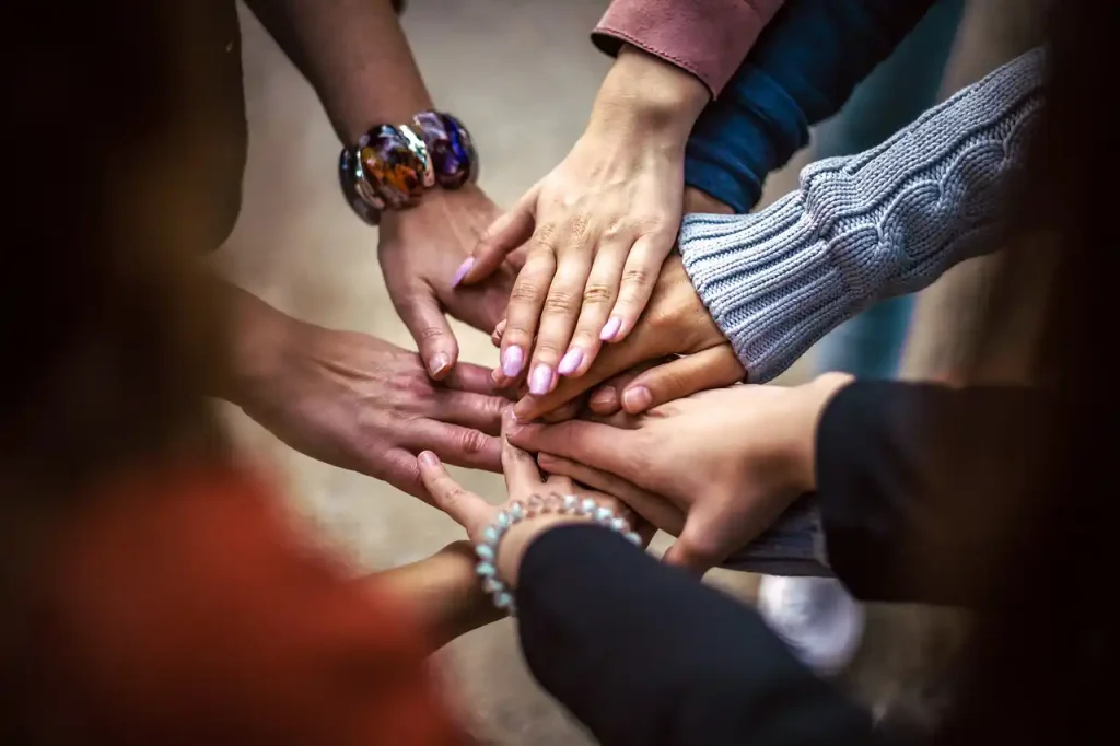 Individual hands of men and women with different skin tones overlapping each other.