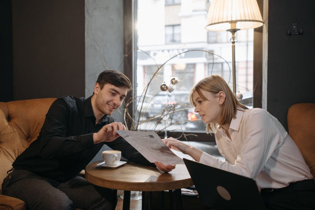 Two people discuss a document while enjoying coffee in a modern café.