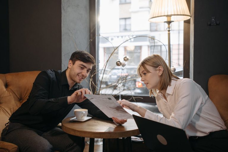 Two people discuss a document while enjoying coffee in a modern café.