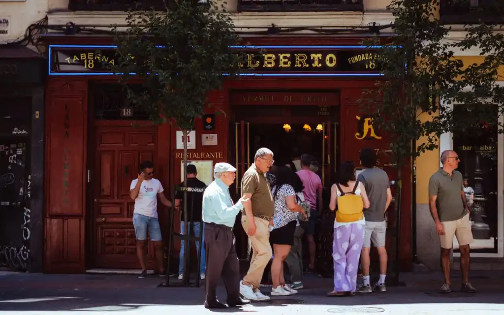 People gathering outside Taberna Alberto in Madrid, Spain, capturing local street life.