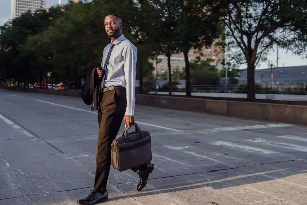 Confident man in business attire crossing an empty urban street on a sunny day.